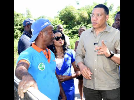 Prime Minister Andrew Holness (right) listens as Garfield Espeut (left), farmer in Golden Grove, St Thomas Eastern, explains the loss he suffered when crops valued at over $17 million were destroyed in the field when flood waters from recent heavy rains im