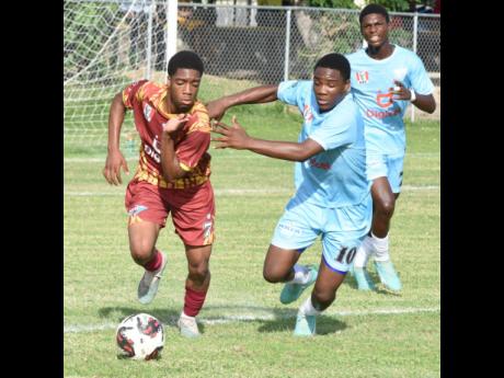 Wolmer’s Boys’ School’s Daquan Duhaney (left) gets by St Catherine High School’s Kadean Young (centre) and his teammate Ronaldo Stewart during an ISSA Walker Cup Knockout football game at The Mico University College yesterday.