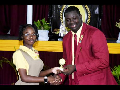 Kiara Burrell collects her special award from Vinceroy Salmon, after being declared the top academic student for grade seven for the 2022-2023 school year.
