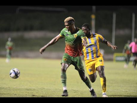 Humble Lion’s Andre Clennon (left) is tackled by Keithy Simpson of Waterhouse during last night’s Jamaica Premier League match at the Stadium East field. Humble Lion won 1-0. 