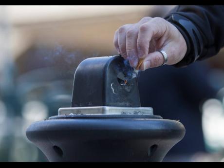 A man stubs out a cigarette in a public ashtray in Paris, France, on October 1, 2015. France will ban smoking on all beaches, public parks, forests and some other public areas as part of a national anti-tobacco plan detailed by the health minister on Tuesd