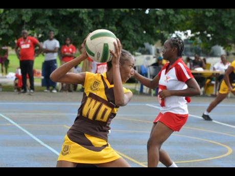 Holmwood Technical wing defence Tasara Campbell (left) catches a ball during a Rural ISSA  Schoolgirl Netball quarter-final game against Morant Bay High School at the G.C. Foster College netball courts yesterday.