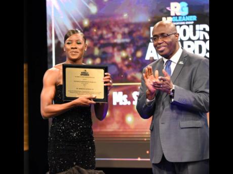 Gary Allen (right), Chairman of the RJRGLEANER Communications Sports Foundation, claps in honour of Shericka Jackson, who won the RJRGLEANER Honour Awards in September.