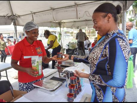 Sanya Kennedy seems excited to try the mango chutney made by Jezreel Farms as owner Majorie Changoo hands her a jar at an exhibition hosted by the Scientific Research Council in St Andrew on Thursday.