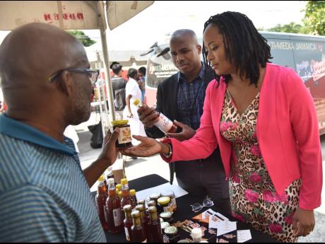 SRC Executive Director Dr Charah Watson (right) Dr Ryan Francis (centre), manager of the agency’s Product Research and Development Division, check out a few honey products with the assistance of Lennox Deane, owner and operator of BeeWise.