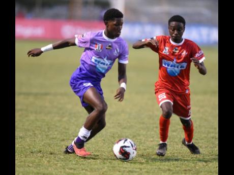 Dujuan Green (left) of Kingston College and  Glenmuir High’s O’Neil Headley battle for the ball during their Champions Cup semi final match at the Anthony Spaulding Sports Complex on Tuesday.