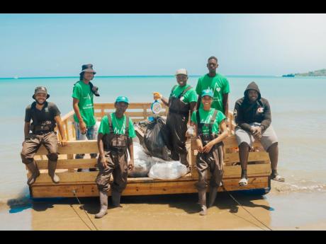 Esirom Foundation members and volunteers pose atop their Pontoon, a waste collection device they created to aid in their efforts. 