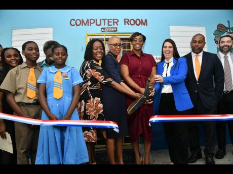 Minister of Education and Youth, Fayval Williams (fourth left), and Speaker of the House of Representatives, Juliet Holness (fourth right), cut the ribbon to officially open a renovated computer room at Clan Carthy Primary School in Kingston on Tuesday. Am