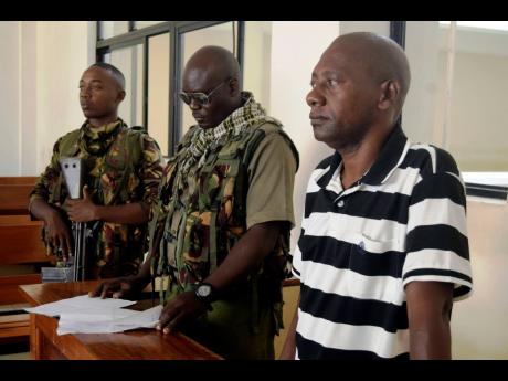 Cult preacher Pastor Paul Nthenge Mackenzie (right) stands at the Malindi Law Courts under tight security yesterday.
