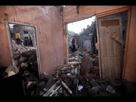 Palestinians look at destruction after the Israeli bombing In Khan Younis refugee camp in Gaza Strip on Friday.