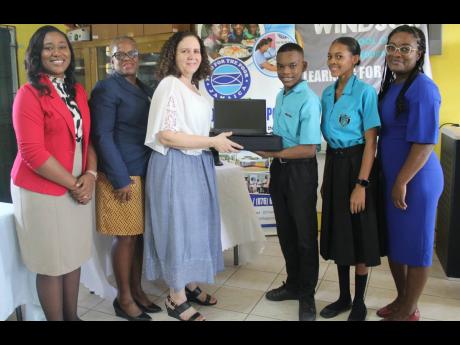 Susan James-Casserly (third left), Food For The Poor projects manager to Jamaica, presents one of the laptops to Windsor School of Special Education student Xavier Brown. Looking on are (from left) Zoya Knight-Samuels, quality assurance officer; Jennifer H