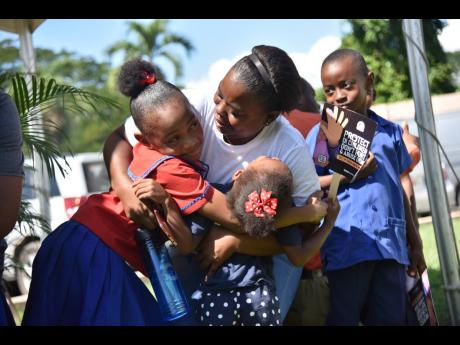Kemisha McLean (centre), a representative from Eve For Life, hugs Sanaa Maxwell (left), a student of St Dominic Prep, and Kalila Hamilton at one of the CPFSA’s Regional Children’s Marches and Social Services Fairs in Linstead, St Catherine, on Friday.