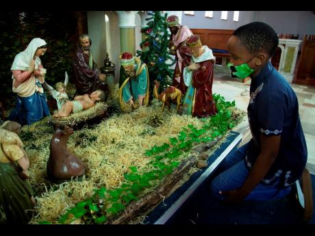 In this 2020 photo a child kneels at a nativity scene prior to a morning Christmas Mass at the Rosebank Catholic Church in Johannesburg.