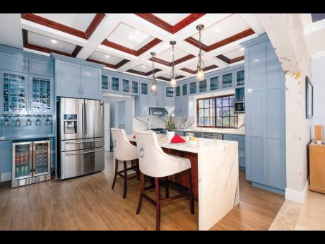 Coffered ceiling, waterfall island, and a kitchen adorned with marble countertops.