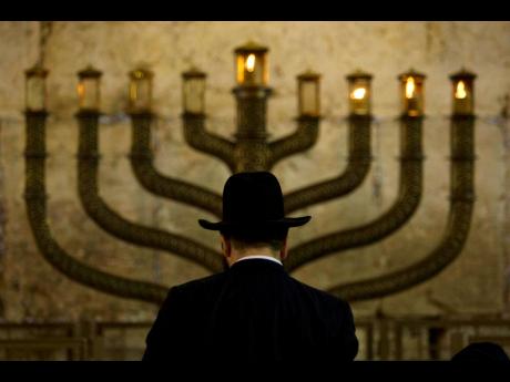An Ultra-Orthodox Jewish man stands in front of a menorah on the third eve of Hanukkah, at the Western Wall, Judaism’s holiest site in Jerusalem’s old city on Sunday, December 13, 2009.