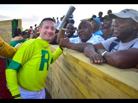 France national, Julien Leparoux, celebrates with fans after steering United States-based horse ROUGH ENTRY to victory in the second running of the lucrative Mouttet Mile at Caymanas Park yesterday.