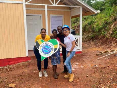 Megahn Swaby (second left) and her son, Johnair Taylor (second right), accepting their new house for Christmas from Marsha Burrell Rose (left), marketing and development manager, Food For The Poor Jamaica, and Dianne Ashton Smith, head of corporate affairs