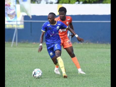 Molynes United’s Rashawn Livingston (left) dribbles past Lime Hall Academy FC’s Tajay Anderson during their Wray and Nephew/Jamaica Premier League match at the Drax Hall  Sports Complex in St Ann yesterday. The match ended in a 0-0 draw. 