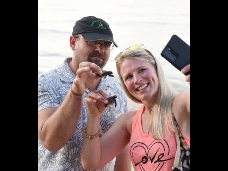 Tourists take a selfie with baby turtles before releasing them into the sea at Gibraltar Beach in Oracabessa, St Mary, on Thursday.