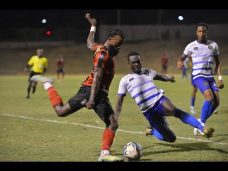 Vere United defender Jadon Anderson (centre) moves in to block a shot by forward  Kimani Arbouine of Arnett Gardens during yesterday’s Jamaica Premier League match at the Stadium East field.  Arnett Gardens won 2-0.