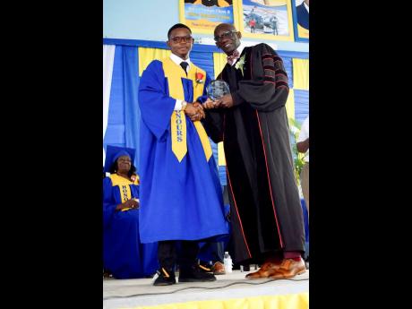  Paul McCalla who earned 11 subjects in the CSEC examinations receives the Top Boy award from Principal Dr. Oneil Ankle at the Jonathan Grant High School’s graduation ceremony recently.