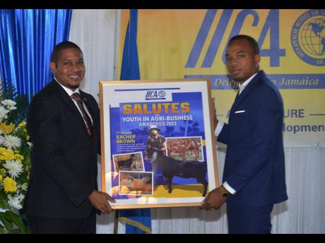 IICA Youth in Agribusiness Services winner Kacheif Brown (right), is presented with a picture frame by Floyd Green, minister of agriculture, fisheries and mining, during yesterday’s IICA Accountability Seminar and Presentation of the 2023 Youth in Agribu