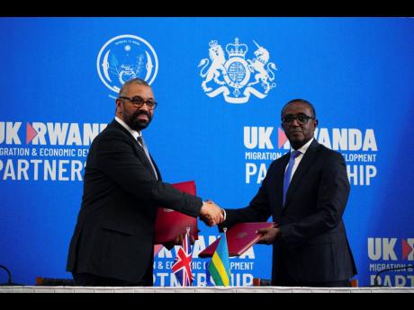 Britain’s Home Secretary James Cleverly (left), and Rwandan Minister of Foreign Affairs Vincent Biruta shake hands after signing a new treaty in Kigali, Rwanda on Tuesday. The treaty will address concerns by the Supreme Court, including assurances that R