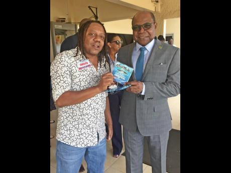 Sean ‘Contractor’ Edwards (left), presents a copy of ‘Tropical House Cruises to Jamaica’ to Tourism Minister Edmund Bartlett. 