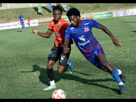 Rohan Brown (right) of Dunbeholden dribbles past Tivoli’s Jah-Neil Wray during their Jamaica Premier League match at the Stadium East field yesterday. The game ended in a 2-2 draw.