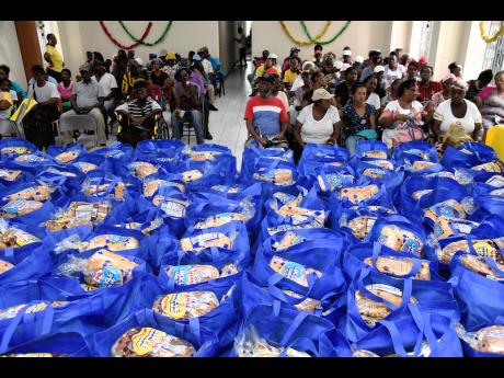 Residents of Central and Western Kingston attend the Salvation Army Eastern Division food distribution headquarters downtown Kingston yesterday, where they received donations of items for Christmas.