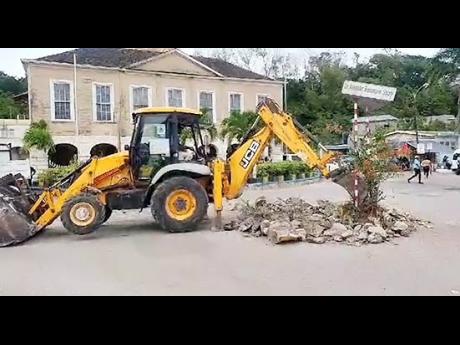 A tractor contracted to the National Works Agency excavating an area at the Sir Alexander Bustamante Square sign in Lucea, Hanover, on Thursday, December 14, 2023. The sign was removed as part of a traffic flow improvement project.