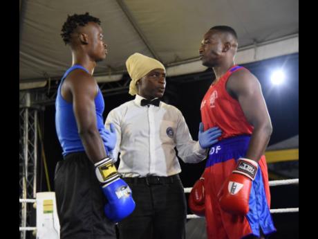 Referee Wayne Roberts (centre) gives last-minute instructions to Kirk Patrick Heron (left) of Port Antonio Boxing Club and Delano McLaughin JDF Gym just before their welterweight amateur boxing match at the  Wray and Nephew Fight Nights series on Saturday 