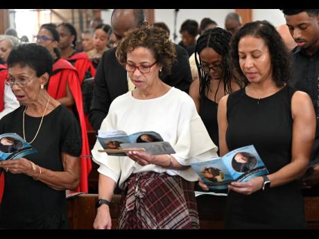 From left: Widow Sheila Baugh and daughters Catherine Baugh and Sarah Cole singing a hymn during Monday’s funeral for Professor Edward Baugh.