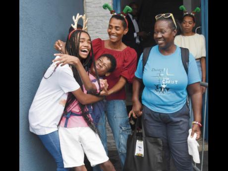 Isiaa Madden (third left), managing director of Dovecot Montego Bay, looks on as her daughter Aziza Brownie is hugged by an excited Balton Cammock during a Christmas treat put on by Madden’s Funeral Home at its Montego Bay location yesterday. Looking on 