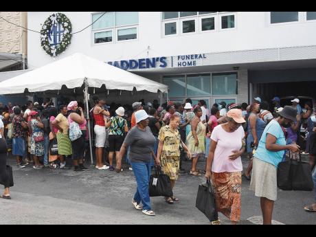 People line up to receive their Christmas food items during Madden’s Funeral Home’s annual Christmas treat at its Montego Bay location yesterday. A total of 500 people were gifted with a bag full of items at the annual event.