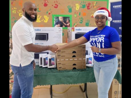 Jason Brown (left), village director at SOS Children’s Village, accepts a donation of appliances and gadgets from Toni-Ann Latty, marketing and public relations officer at the Unicomer Group, on Thursday. 