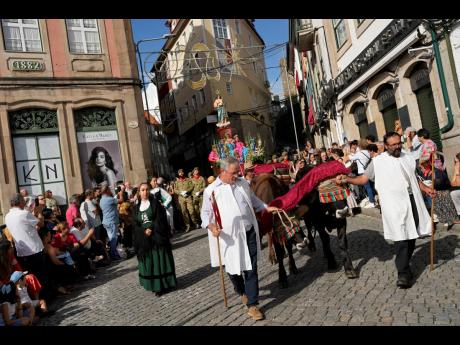 Pairs of oxen pull a boat-shaped float with an iconic century-old sacred image of Virgin Mary breastfeeding infant Jesus standing on the bow, during the Our Lady of Remedies procession in the small town of Lamego, in the Douro River Valley, Portugal, on Fr
