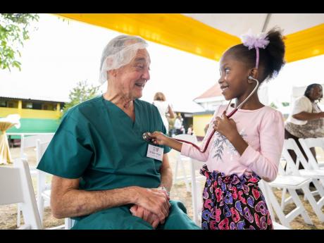 Dr Gavin Wright (left), chairman of Chain of Hope, has his heart checked by six-year-old Oneila Dunn, a past beneficiary of the charity, as it celebrates its 20th year of cardiac care to Bustamante Children’s Hospital in St Andrew. Wright was the anaesth