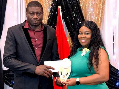 Sergeant Phillip Gordon (left), of the Westmoreland Division of the Jamaica Fire Brigade, collecting the Superintendent Award from Shermaine Hartley-Drummond, an educator who was the master of ceremonies at the division’s end-of-year awards banquet at Ro