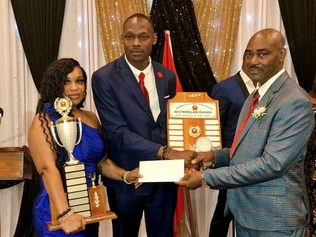 Superintendent Rudolph Seaton (right), head of the Westmoreland Division of the Jamaica Fie Brigade, presents Sergeant Ryan Crooks with his Firefighter of the Year award while Crooks’ spouse, Sheredon Gayle, holds one of his trophies.