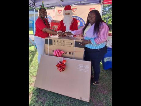 Janet Richards (left), managing director and founder of the Janet Richards Foundation, presents a washing machine and television set to Cordell Howell-Huie, administrator at the Mustard Seed Communities Children’s Home in Adelphi, St James on Christmas E