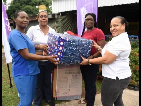 Karelle McCormack (second left), public relations and marketing manager, 138 Student Living Jamaica Limited, and human resource manager Cheryl Clarke (right) present gifts to Saline Maxwell (left), caregiver, City of Refuge Children’s Home, and senior ca