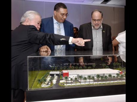 Prime Minister Andrew Holness (centre) and Opposition Leader Mark Golding (right) look on as National Bakery’s Managing Director and Chairman, Butch Hendrickson, points to a section of the model plant plan. National Bakery is constructing a state-of-the-