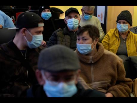 People wearing face masks as a precaution wait for a doctor appointment inside a hospital in Barcelona, Spain, Monday, January 8, 2024. Regional and national health chiefs are meeting Monday to decide whether to extend mandatory mask-wearing to all health 