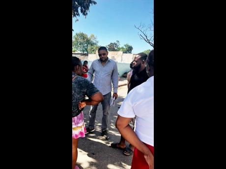 Councillor Eugene Kelly (foreground) speaks to residents who lost practically everything in a fire that gutted their premises at Swettenham Road in Whitfield Town on Wednesday. Twenty-five people, including children, were left homeless because of the infer