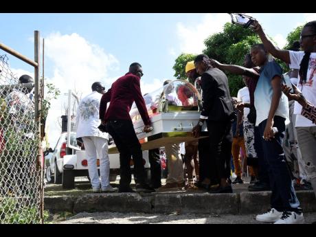 Pallbearers remove the body of Robert Lee Malcolm, more popularly known as ‘Gully Bop’, from the hearse-drawn caravan, shortly after it arrived at the Ranny Williams Entertainment Centre.