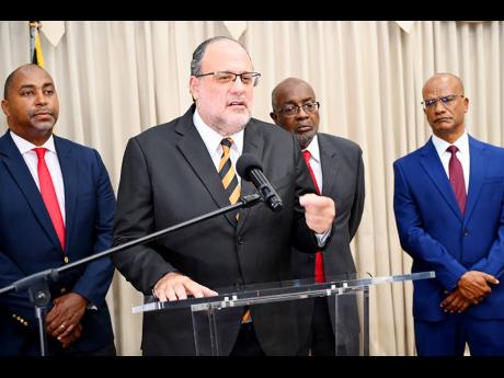 Mark Golding (second left), leader of the Opposition and People’s National Party (PNP), speaking at a press conference at the Office of the Leader of the Opposition yesterday. Looking on are (from left) Julian Robinson, MP, shadow minister on finance and