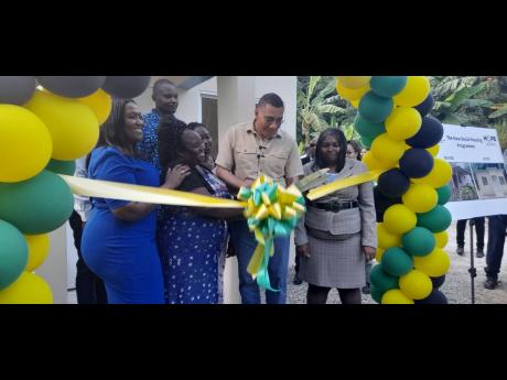 Prime Minister Andrew Holness (second right) takes part in the ribbon cutting for the handover of a house to Gillian Coleman (right) in St Catherine on Wednesday.
