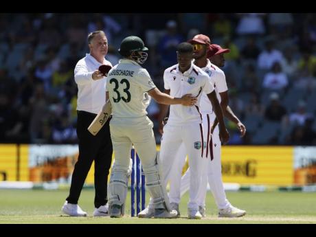Australia’s Marnus Labuschagne (second left) consoles West Indies’ Shamar Joseph (centre)  after Australia won by 10 wickets on the third day of the first  Test match in Adelaide, Australia yesterday.
