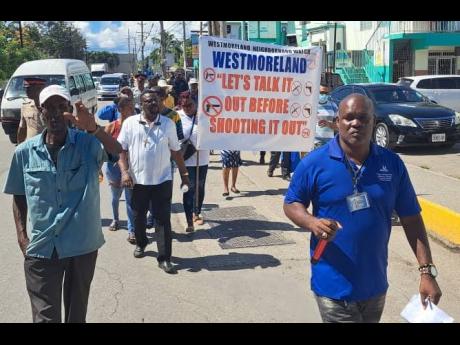 Bishop Oneil Russell (right), head of the Ark of the Covenant Holy Trinity Church in Westmoreland, leads a group of residents, police officers and members of the Restorative Justice Centre in a peace march through sections of Savanna-la-Mar.